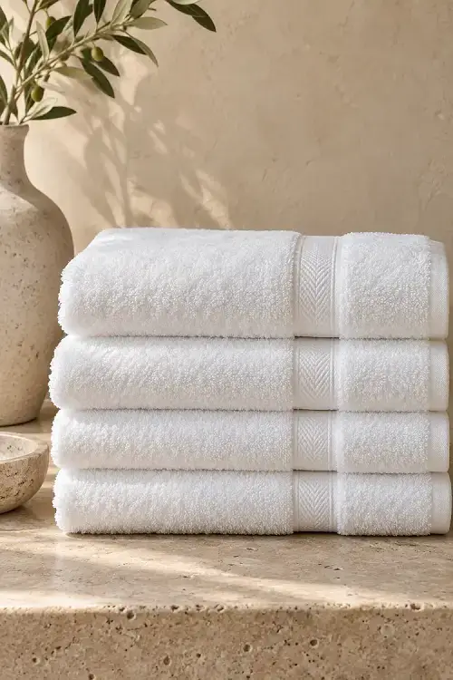 Stack of white cotton hotel towels on a stone counter